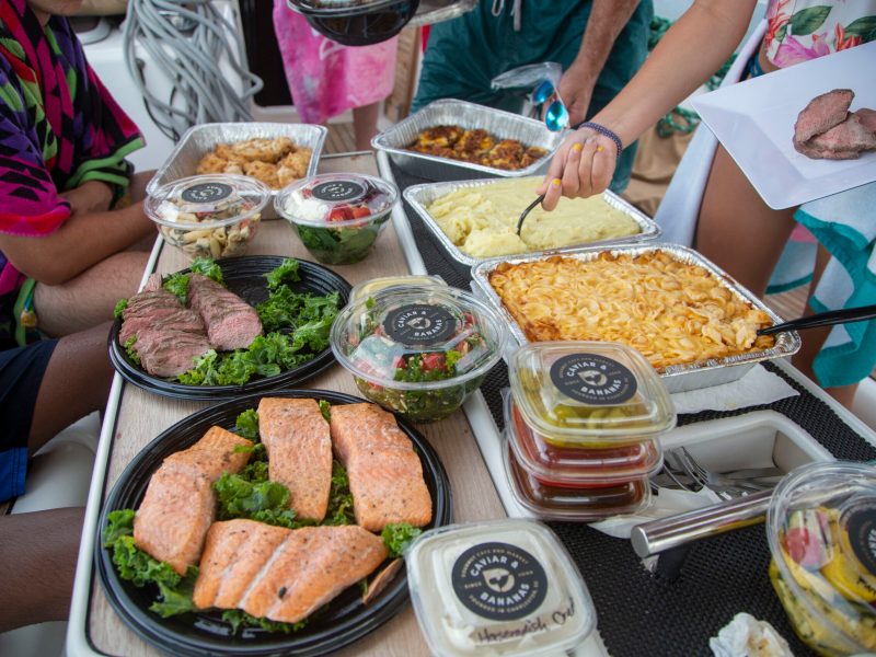 a group of people sitting at a table with trays of food