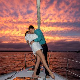 a couple kissing in front of a sunset