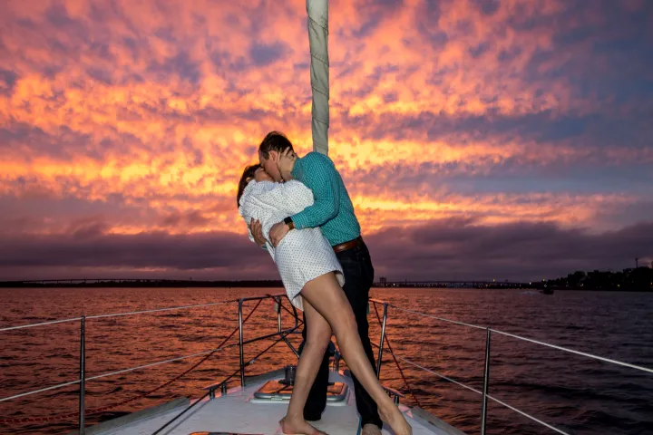 a couple kissing in front of a sunset