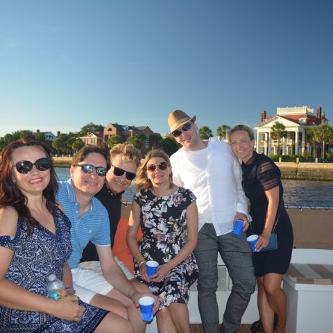 a group of people posing for a picture next to a body of water