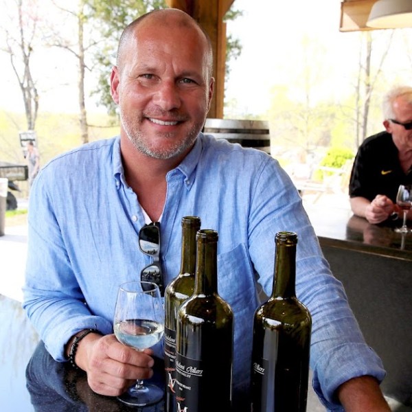 a man standing next to a bottle of wine