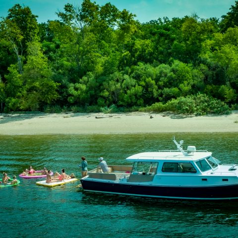 a boat floating along a river next to a body of water