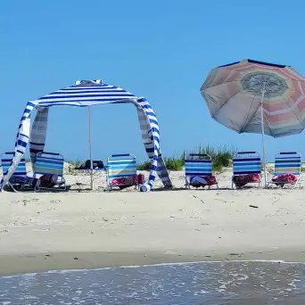 a group of people at a beach umbrella in the sand