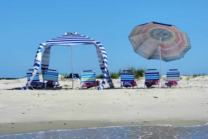 a group of people at a beach umbrella in the sand