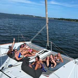 Six people relaxing on a catamaran deck, enjoying a sunny day on the water.