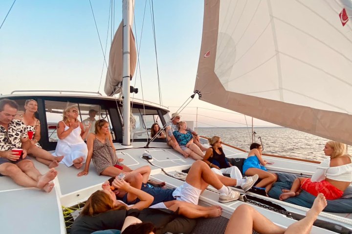 bachelorette party relaxing on a sailboat deck at sunset.