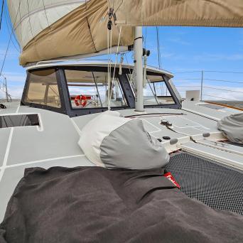 View from a boat deck with sail and covered equipment, under a clear blue sky.