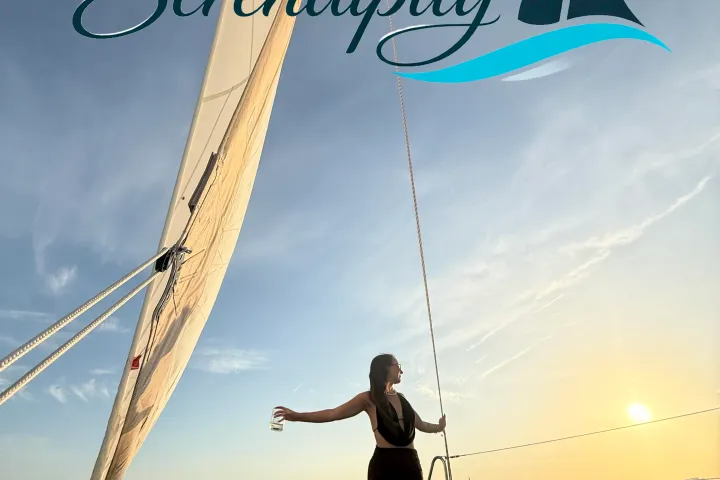 Woman on a sailboat at sunset under the word 'Serendipity' with logo.