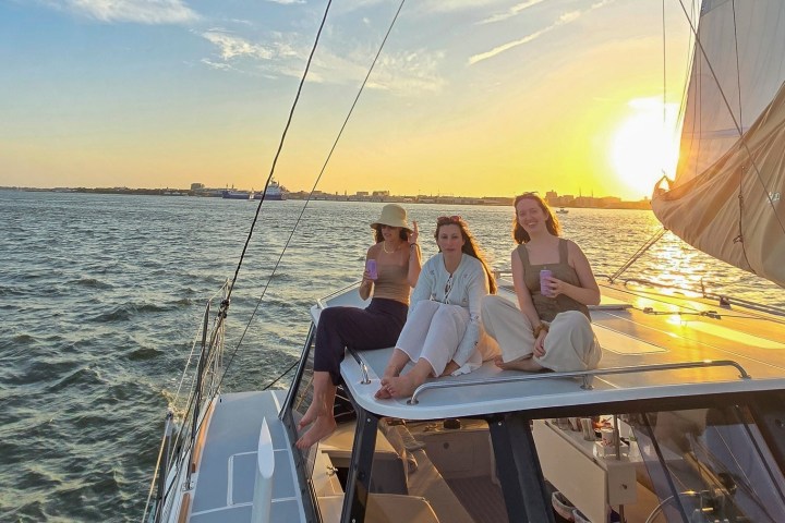 Three people on a boat at sunset, sitting on deck, enjoying the view.